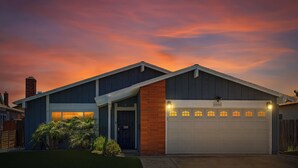 Una casa a due piani con garage, una sezione in mattoni sulla destra e un tetto scuro.