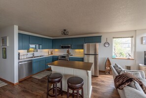 Une cuisine moderne avec des meubles bleus, des appareils en acier inoxydable et un îlot central doté de tabourets.