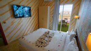 Ein Hotelzimmer mit Bett, Wandfernseher, Kleiderschrank und Blick nach draußen.