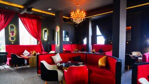Ein modernes Interieur mit roter Sitzmöblierung, einer Kristallleuchtre und einem Klavier.