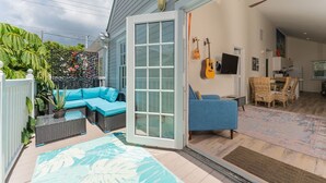 A modern living room with a glass door leading to a patio area, featuring a sofa, a coffee table, and a TV. - MAI TAI TERRACE - KEY WEST (Key West)