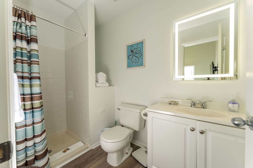 Une salle de bain équipée d’une douche, de toilettes, d’un lavabo et d’un miroir.