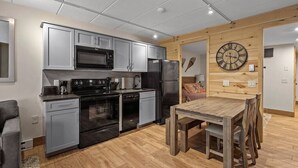 A modern kitchen with stainless steel appliances, grey cabinets, and a wooden dining table.