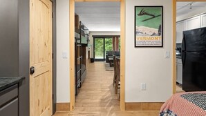 A modern kitchen with a black refrigerator, wooden cabinets, and a wooden door.