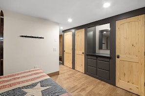 Cozy retreat with a geometric-patterned quilt, a wardrobe, and a mirror.