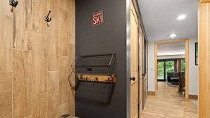 A hallway with wooden flooring, a wall-mounted ski rack, and a sign indicating a ski facility.