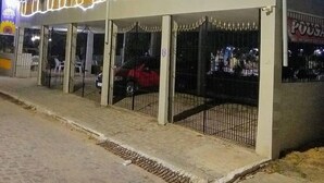 A building with a covered outdoor seating area, a gated entrance, and a sign that reads "POUSHA".