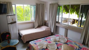 A hotel room with two beds, a small table with a vase, a television, and curtains.