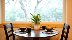 A dining table with four black bowls and a potted plant in the center, set against a window with a view of trees. - Red Mountain Suite 1 mile to Sequoia Natl Park! (Three Rivers)