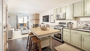 Een moderne keuken met lichtgroene kastjes, een centraal kookeiland en een zithoek met een bank en stoelen.