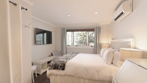 Een slaapkamer met een bed, nachtkastje, lamp en een raam met gordijnen.