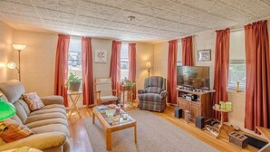 Een gezellige woonkamer met een bank, fauteuils, een salontafel, een televisie en een open haard.