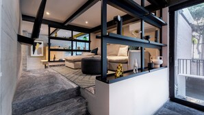 Un interior moderno con una escalera, un sofá y una estantería con objetos decorativos.