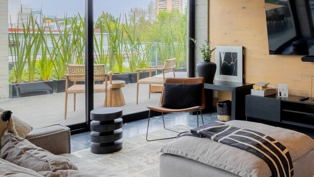 Una sala de estar moderna con un ventanal grande, un sofá, una mesa de centro y un televisor.