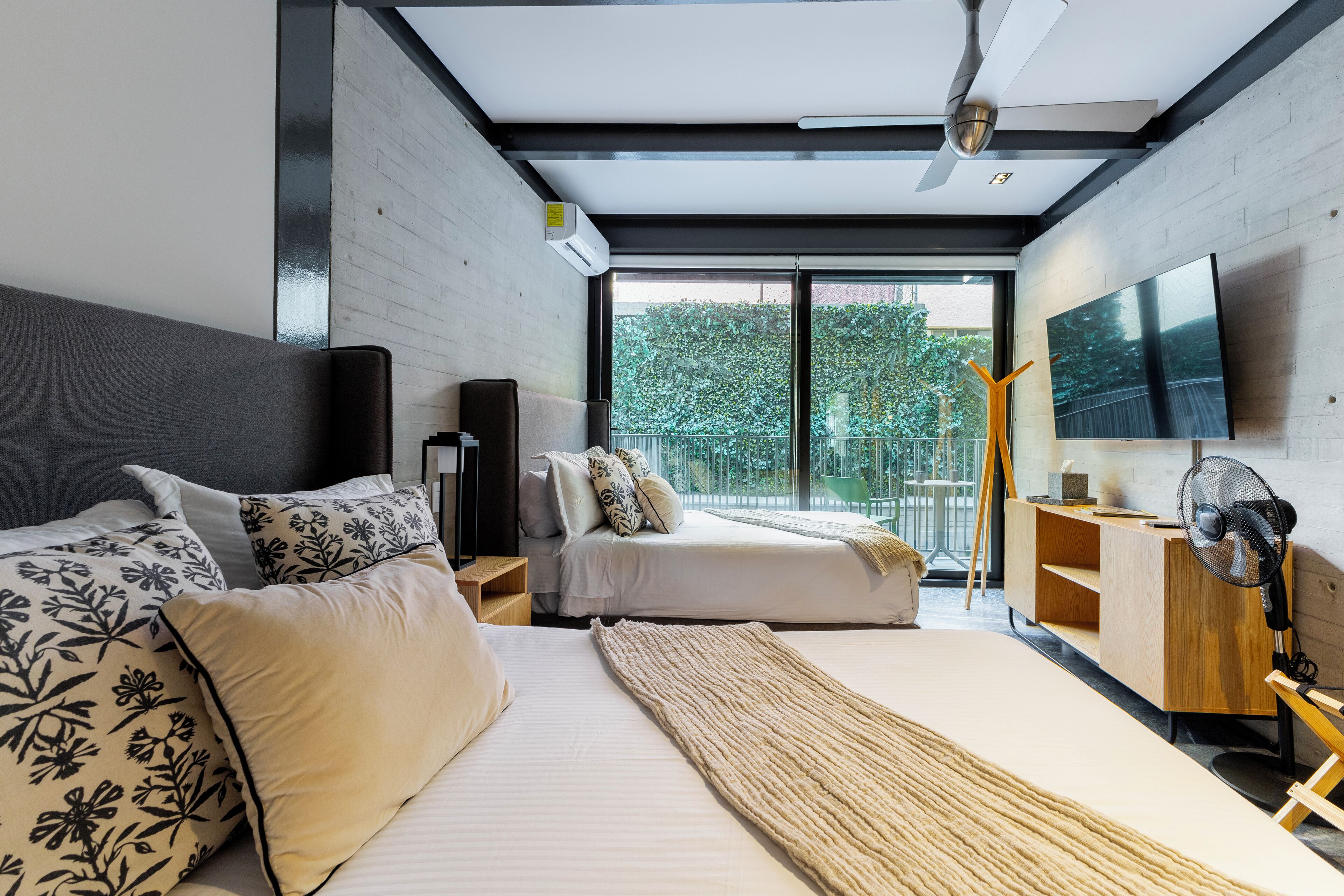 Un dormitorio moderno con una cama grande, una cama más pequeña, un escritorio y un televisor.