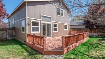A two-story house with a front deck and a fenced backyard.