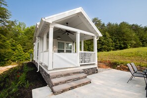 A white house with a porch, stone steps, and a ceiling fan. - The Jocassee Tiny House (Salem)