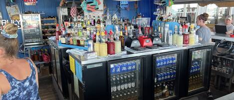A bar area with a variety of liquor bottles and a neon sign for Budweiser.
