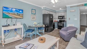 A compact living space with a dining area, kitchen, and seating area. - Sand In My Boots<br>Condo Beach view, 3 bed, 1 bath (Murrells Inlet)