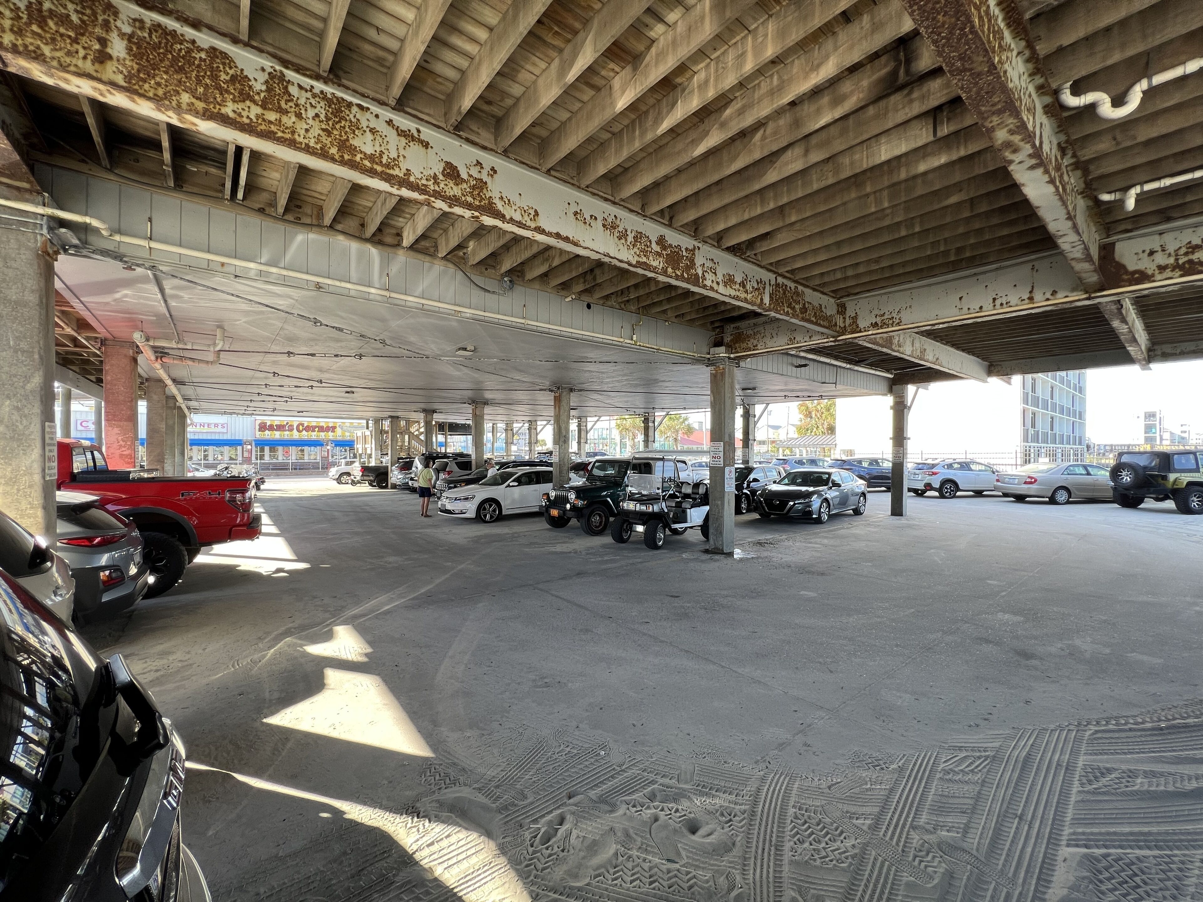 A parking garage with multiple levels and a variety of vehicles, including cars and a red truck.