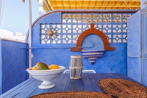 Una habitación con paredes azules, una mesa de madera, un frutero, un tambor y un adorno en la pared.
