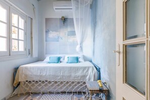Un dormitorio con cama, ventana, aire acondicionado y una lámpara fijada a la pared.