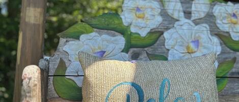 A bench with a cushion labeled 'Relax' and a floral mural in the background.