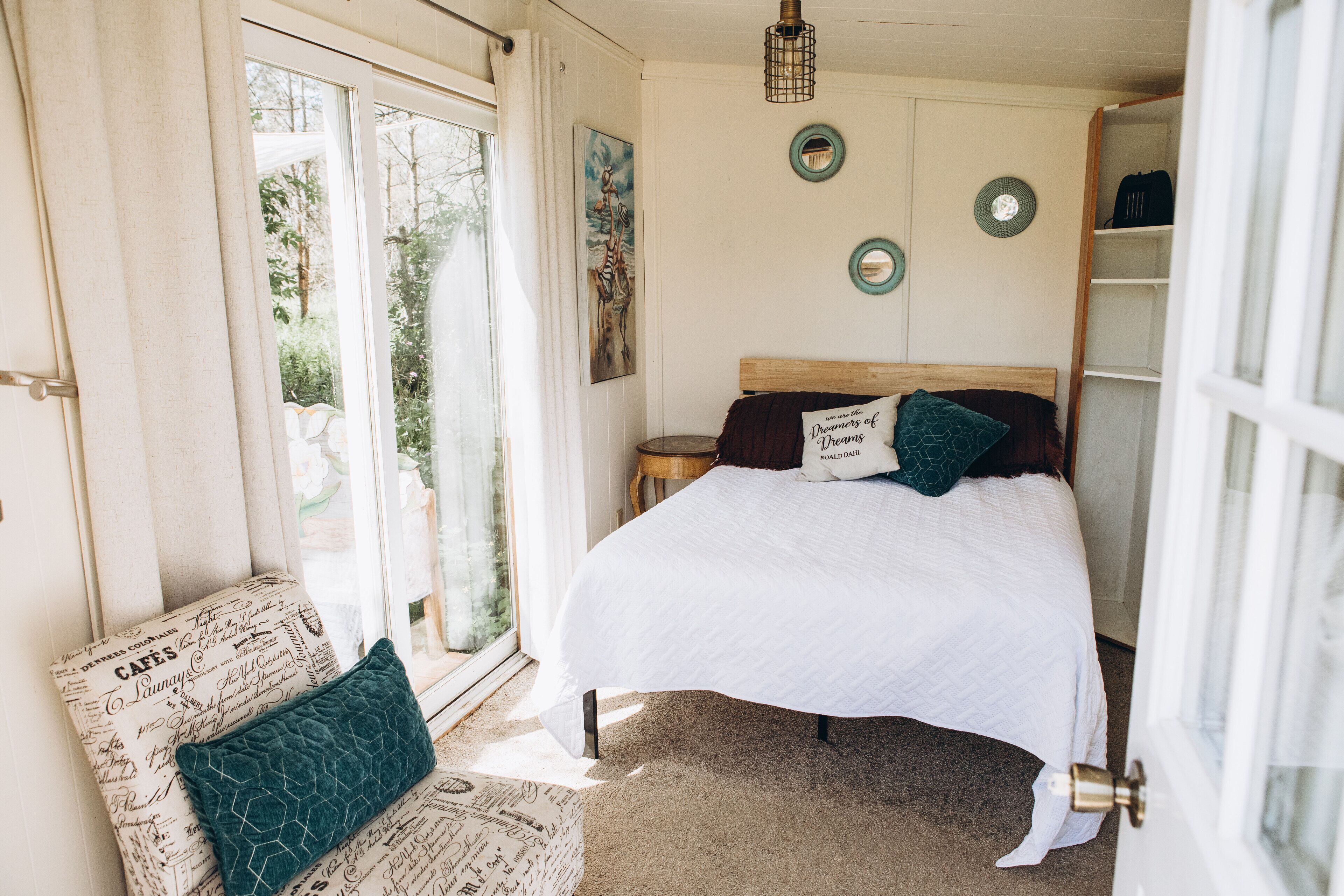 A bedroom with a bed, a chair, a window, and a door.