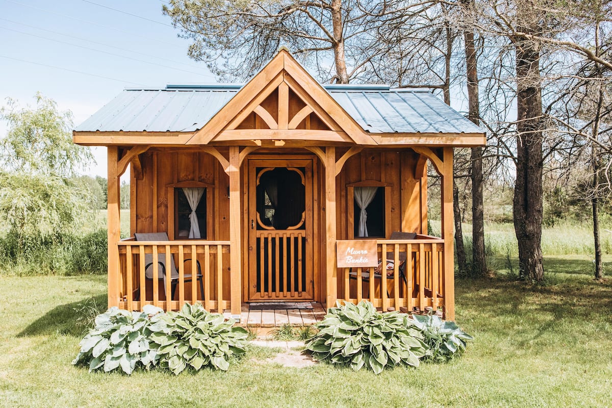 A wooden cabin with a porch, a sign reading "Myrna Bunkie," and a metal roof.