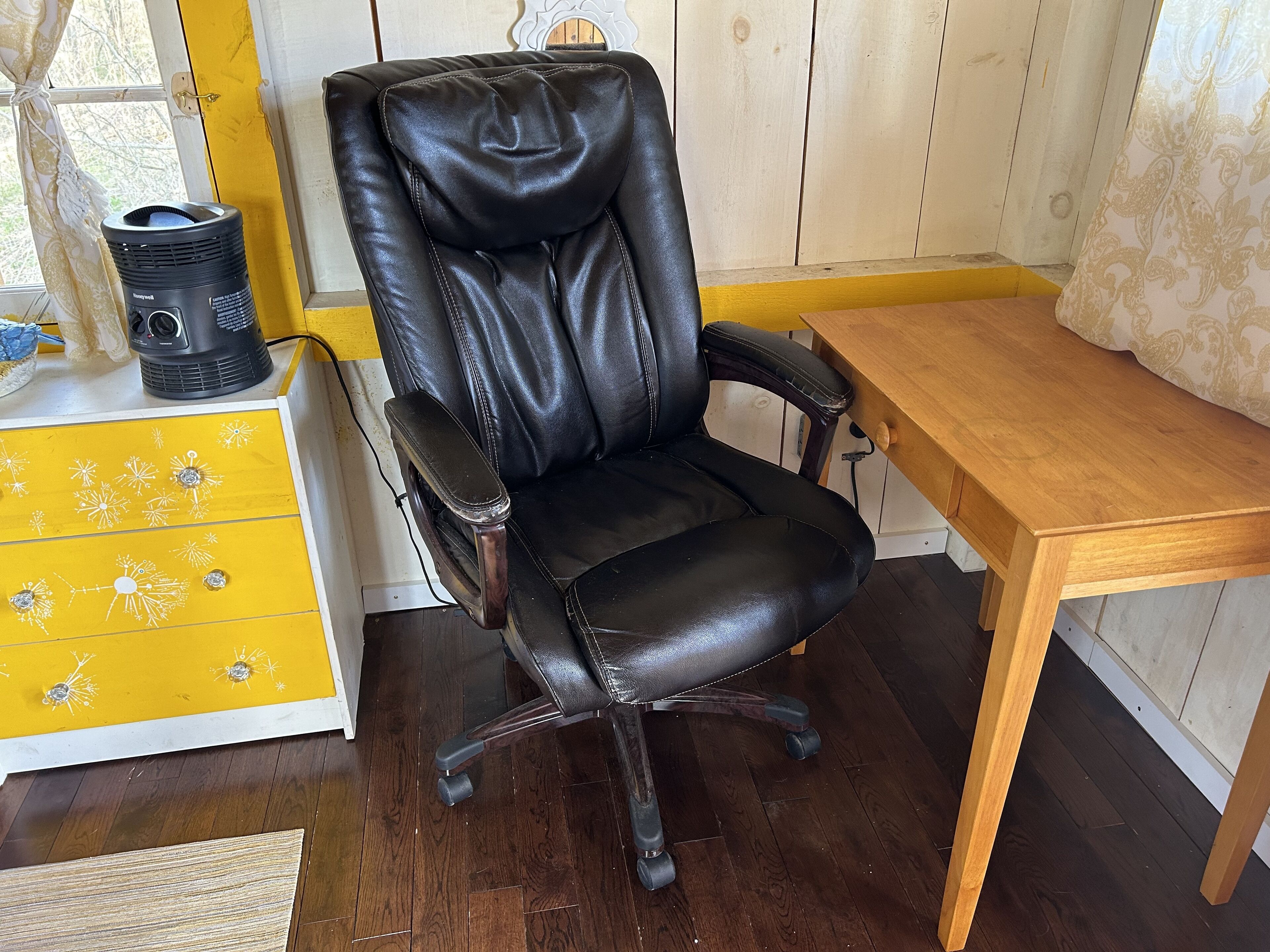 Una silla de cuero negra para oficina con una mesa de madera al lado.