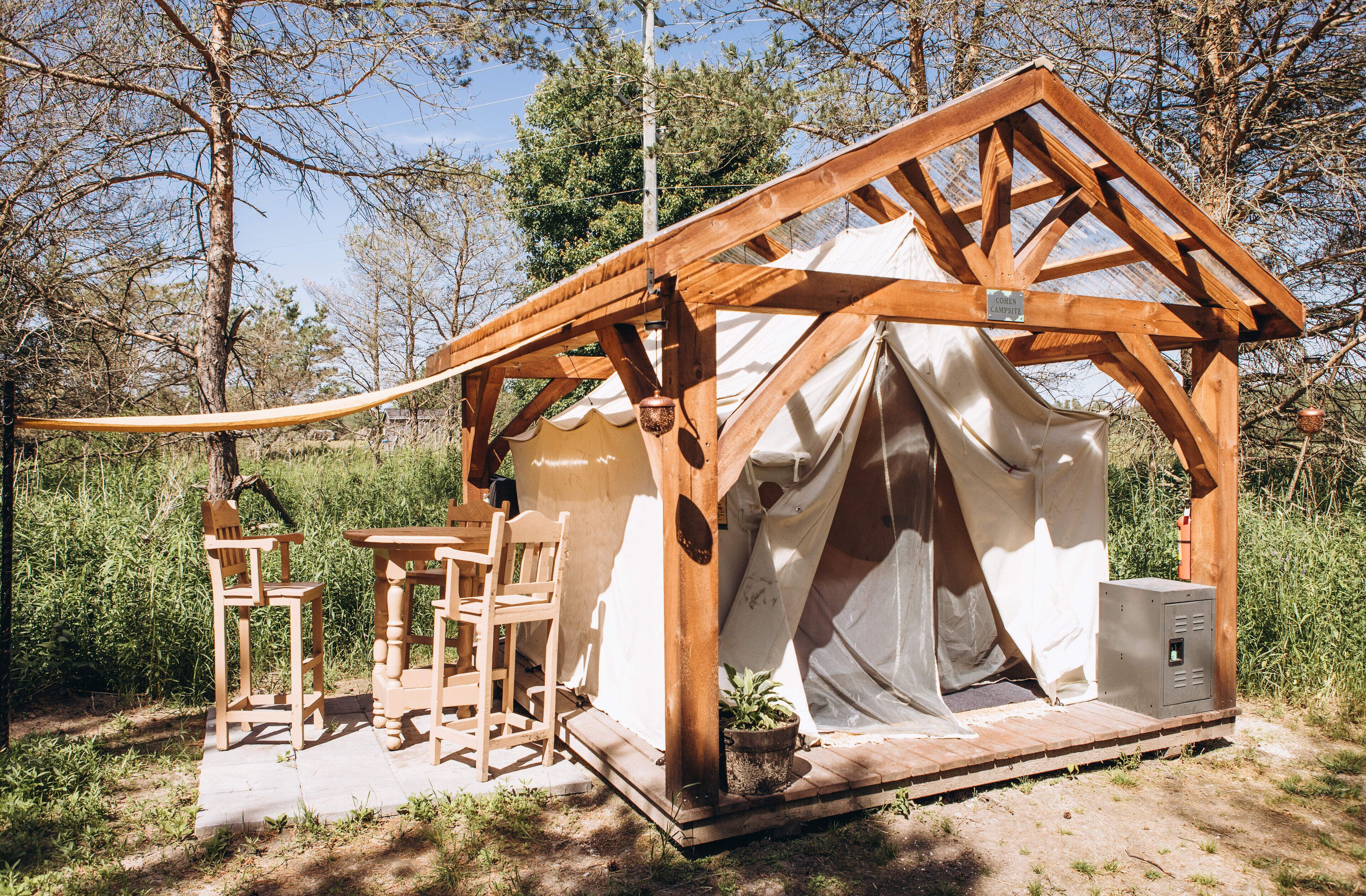 Une structure en bois avec une tente, une table et deux chaises.