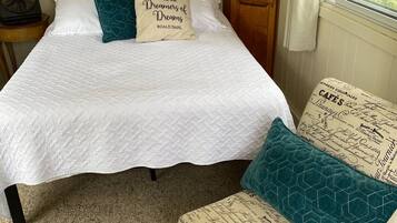 A bedroom with a bed, a nightstand, a wooden wardrobe, and a window with curtains.