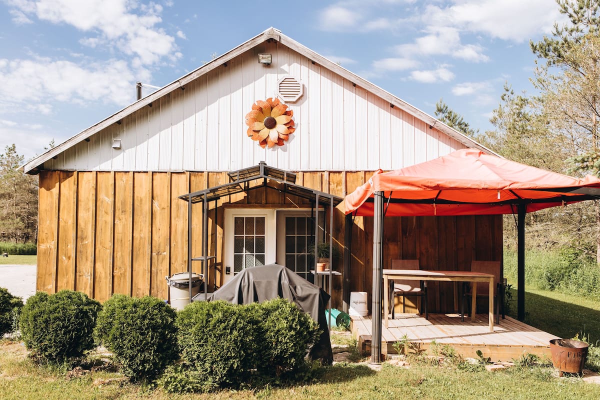 A wooden barn with a covered patio and a large flower decoration on the wall.