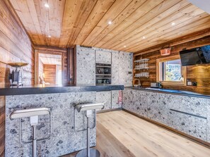 Eine moderne Küche mit Holzboden, Granitarbeitsplatten und einer Bar mit Hockstühlen.
