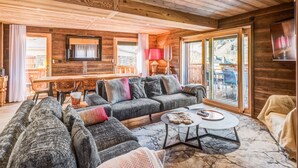 A cozy wooden interior with a sofa set, a coffee table, and a dining area with a table and chairs.