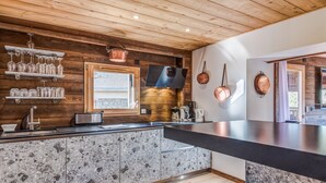 A modern kitchen with wooden accents, granite countertops, and copper cookware.