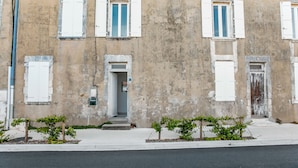 Un edificio con varias ventanas, una puerta y un pequeño jardín con plantas.