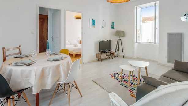 Una sala moderna con comedor, televisor y sofá.