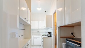 Una cocina moderna con armarios blancos, horno integrado y cafetera.