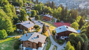 A residential area with houses, a tennis court, and a mountainous backdrop. - Appartement Bridan - Welkeys (Megève)