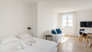 A hotel room with two beds, a desk, a chair, a TV, and a window with curtains. - Appartement Portolan - Welkeys (Antibes)
