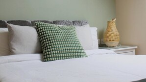 A bed with white bedding, a green textured pillow, and a white vase on a bedside table. - 1 Bed Loft - Sleeps 2 - Parking - Wifi (Newport)