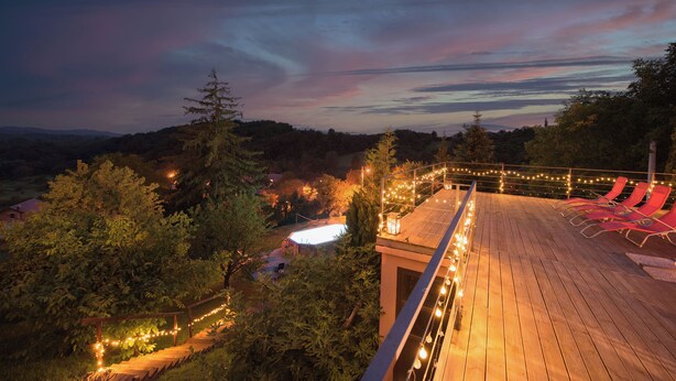 A wooden deck with string lights, red lounge chairs, and a pool in the background. - Villa Chill House Keti - private pool and jaccuzzi (Kuzminec)