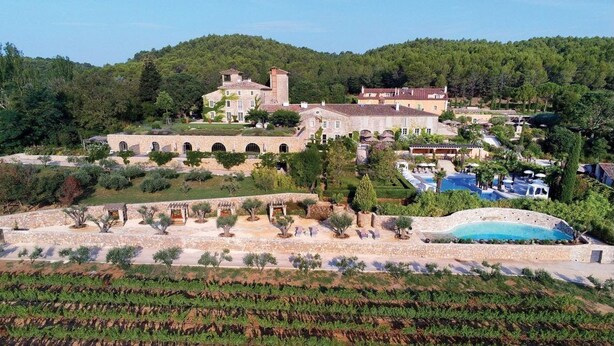 Un vaste domaine doté d  ’une piscine, d’un vignoble et de plusieurs bâtiments reliés par des arcades.