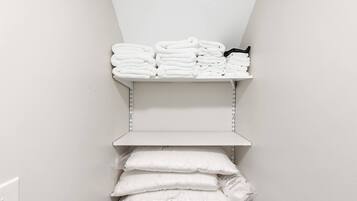 A storage area with shelves holding folded towels and a stack of pillows.
