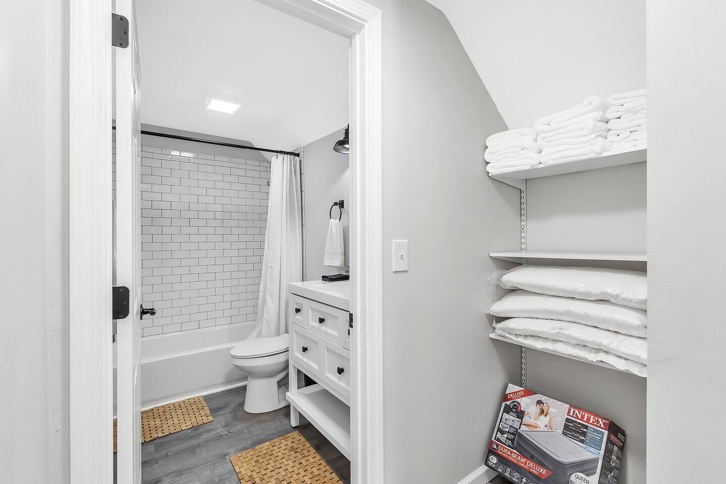 A bathroom with a white toilet, a shower, a white sink, and a towel rack.