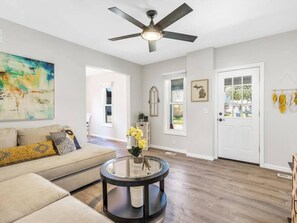 Relax in this stylish living room with a large window and ceiling fan.