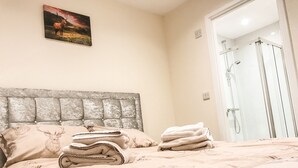Une chambre à coucher comprenant un lit, une tête de lit, un tableau et un espace douche.