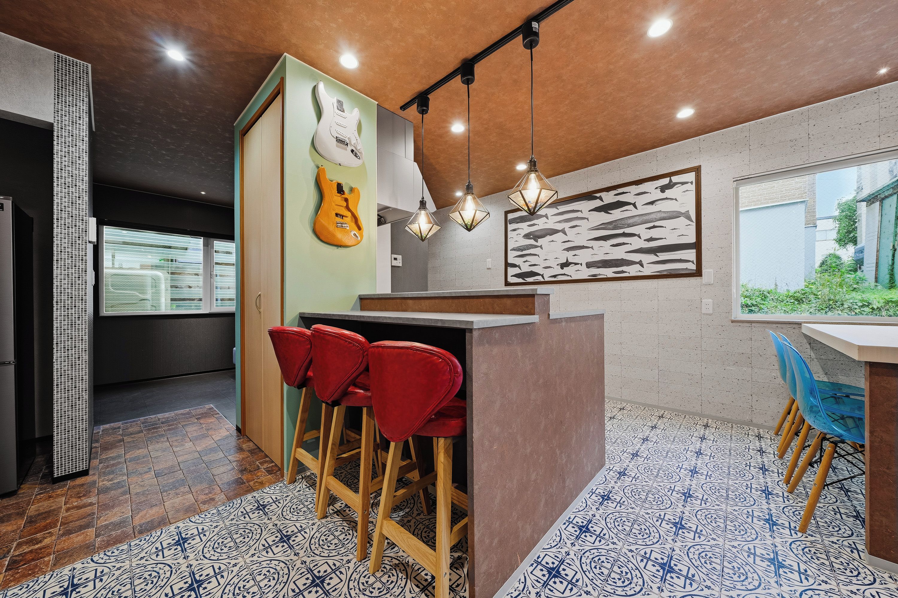 Een moderne keuken met een bar, rode barstoelen en een kunstwerk van vissen.