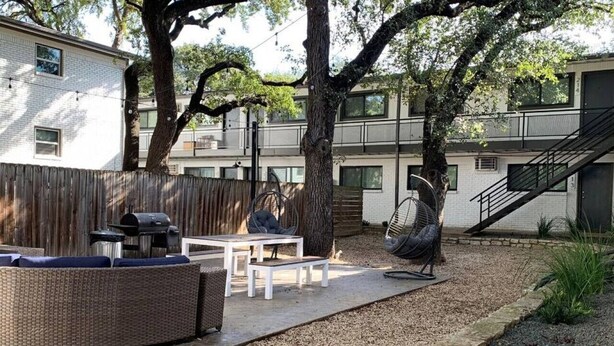 Un patio al aire libre con un sofá de mimbre, una parrilla y un ventilador.